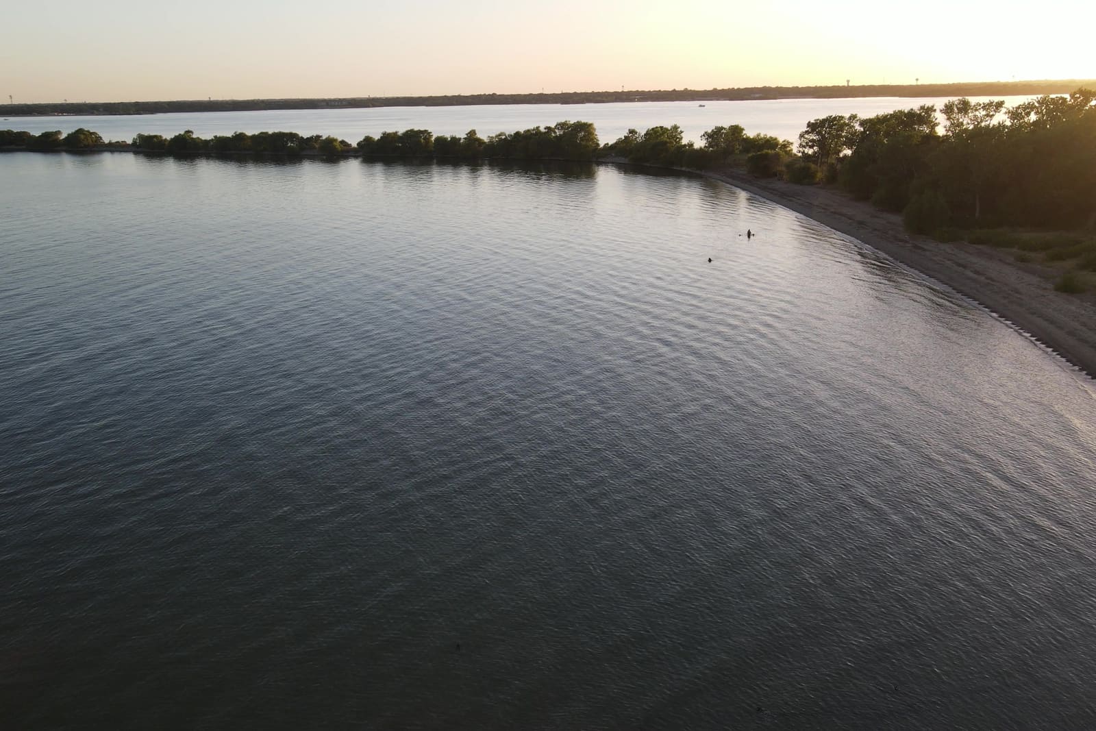 The shoreline curve of The Cut at dusk, seen from the air — still water meeting the darkening beach
